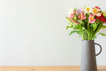 Colorful flowers in a cement vase on a wooden table with copyspace