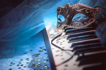 Carnival mask and piano keyboard with star-shaped confetti.