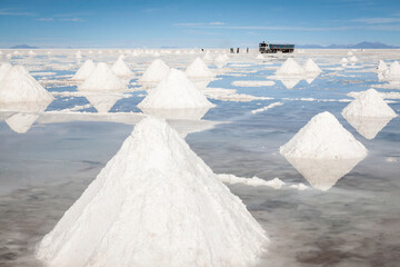 Fototapeta na wymiar Horizontal view of infinite piles of salt in the Salar de Uyuni­. In the background -far away- workers load salt into a large truck, Bolivia