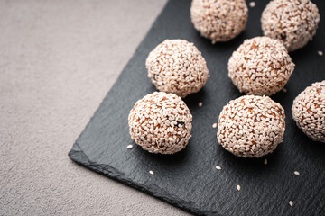 Vegetarian truffles from dates and white sesame on a slate Board close-up view from above