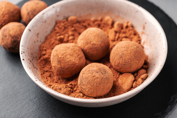 Date candy balls in a plate with carob on a slate Board close-up