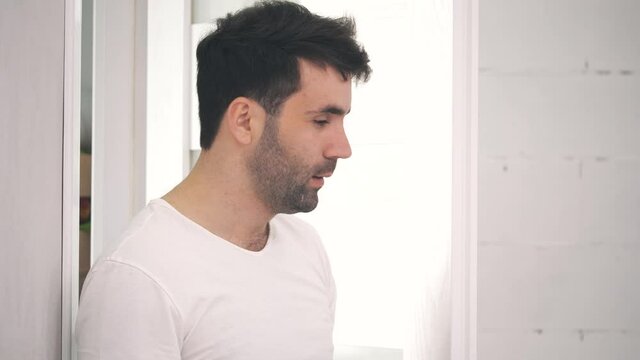 4k slowmotion video of tired man kissing a bottle of beer and closing the door.