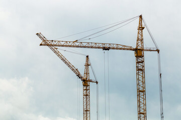 Two yellow construction cranes and blue sky on the background. Industrial landscape. Construction of residential buildings. Business concept.