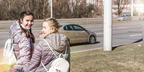 girls walking with backpack on city street in spring day