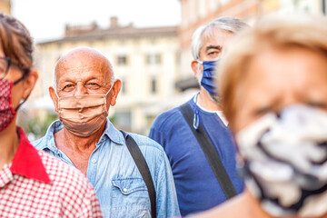 Crowd of people walking down the city streets with face mask on - Camera focusing an old man - New lifestyle