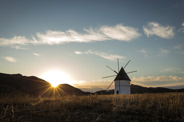 Old white Spanish windmill at sunset with blue sky and fluffy clouds in Cabo de Gata-Níjar Natural Park in southern Spain