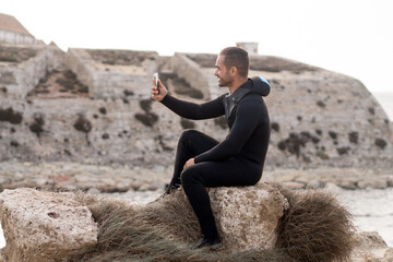 Diver sitting on a rock taking a selfie