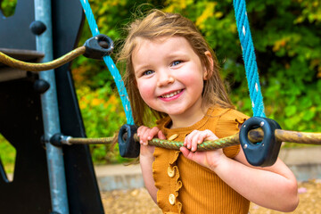 Happy Smiling Child Girl Playing At Playground Outdoors In a nice Park