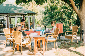 Family sitting outdoors and using laptop and smartphone