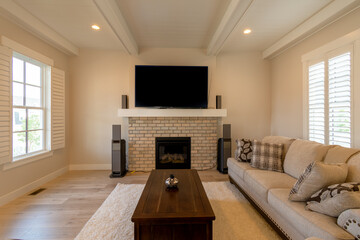 A staged shot of a cozy living room with a fireplace and a mounted big screen television.