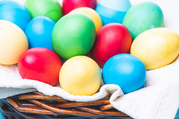 basket with colorful Easter eggs on a blue wooden background, selective focus, tinted image