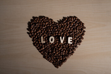 Coffee beans in the shape of a heart and the inscription love on a wooden table