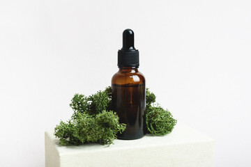 Brown serum glass bottle with pipette with the green moss. Natural Organic Spa Cosmetic concept. Front view.