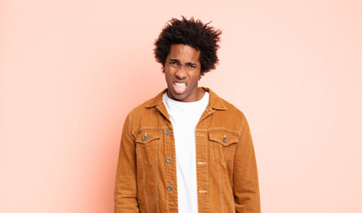 young black afro man feeling disgusted and irritated, sticking tongue out, disliking something...
