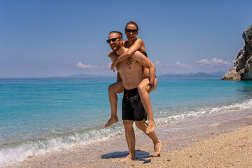 Young man carrying girlfriend on his back along the beach