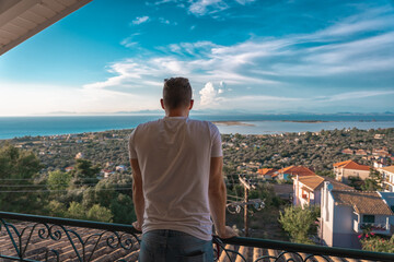 Fototapeta na wymiar Man enjoys seaside viewpoint from balcony