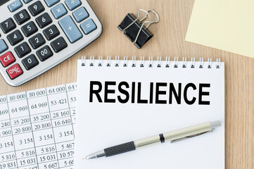 RESILIENCE words on an open notebook on an office desk. Business concept