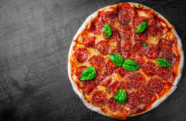 Pepperoni Pizza with Mozzarella cheese, salami, Tomato sauce, pepper, Spices and Fresh basil. Italian pizza on wooden table background
