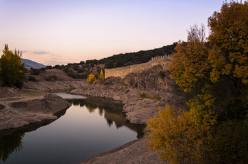 Obraz na płótnie Canvas Walls of Buitrago de Lozoya reflected in the waters of Lozoya river at sunset, Madrid, Spain