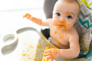 A happy little cute daughter with mash food everywhere