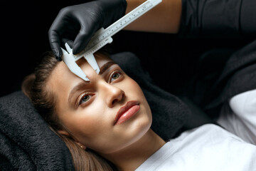 Brow artist measuring eyebrows with the ruler