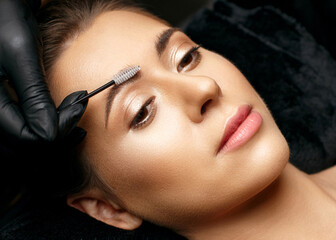 Cosmetician hand combing eyebrows