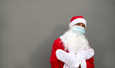 Santa Claus with white beard in red coat in a medical mask. Christmas in the coronavirus pandemic, seasonal diseases, SARS and pneumonia in the holidays. Protection from viruses in the new year. Gray 