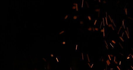 Background of feint blurred orange sparks from fire against black with copyspace - Powered by Adobe