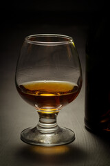Bottle and glass of brandy on a wooden background.