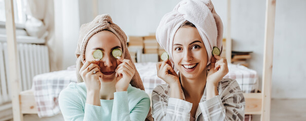 Two girls make homemade face and hair beauty masks. Cucumbers for the freshness of the skin around the eyes. Women take care of youthful skin