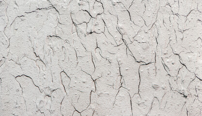Heavily cracked stucco wall texture, macro shot. Grainy and fractured surface. Old wall background.