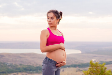 young pregnant woman does yoga outdoors. Yoga at sunset