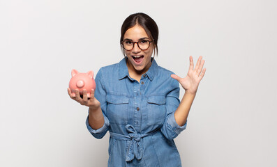 young hispanic woman feeling happy, excited, surprised or shocked, smiling and astonished at...