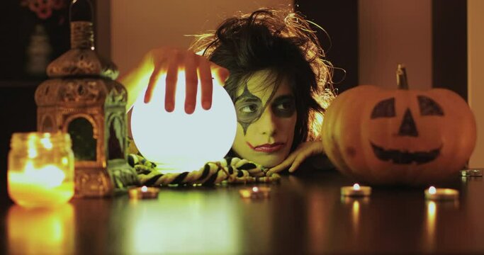 Female with scary halloween mask with pumpkin and crystal magic ball. 