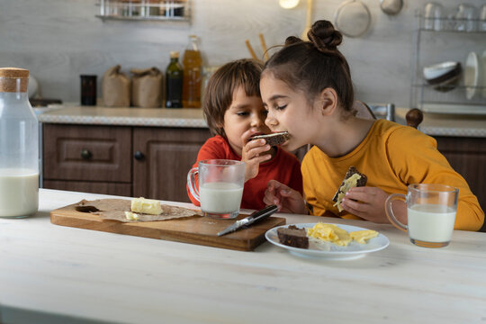 Children Spread Chocolate Paste On Toast Bread In The Kitchen Background. Breakfast Happy Family Having Fun With Food