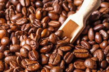 Freshly roasted coffee beans background.Dark roasted coffee beans with scoop on wooden background.