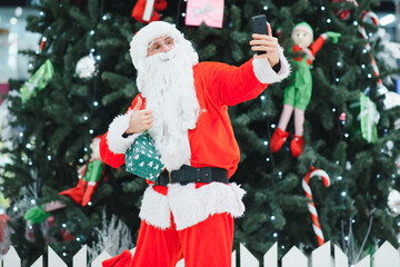 Santa Claus the background of the Christmas tree in the lobby of the modern shopping mall.