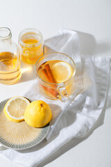 Hot Toddy cocktail drinks with lemon, honey and cinnamon stick in glass on white background. Spiced winter drink