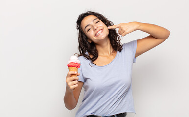 young hispanic woman smiling confidently pointing to own broad smile, positive, relaxed, satisfied...