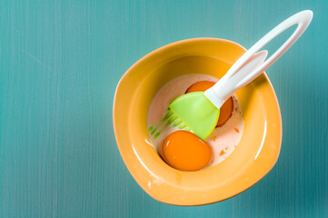 Egg yolk and milk in a bowl with a pastry brush. Top view, copy space for text.