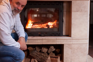 A mature man with a beard squatted near the fireplace