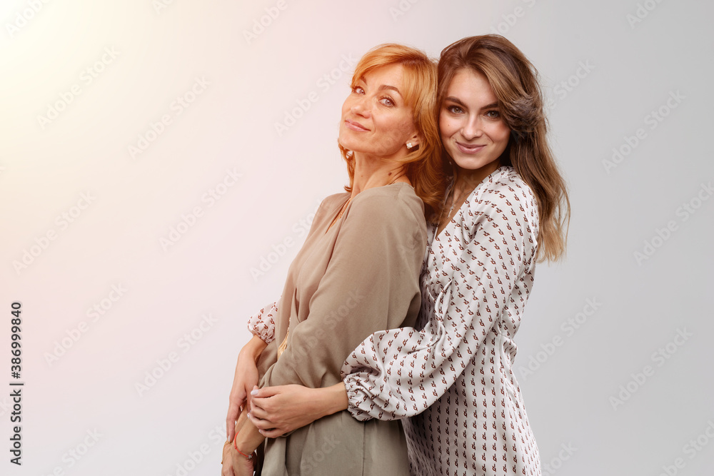 Wall mural happy beautiful women: mother and adult daughter closeup portrait isolated on white background