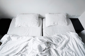 Top view double beds in the hotel. Messed bed with crumpled white pillow and blanket in the morning after wake up, Interior white room in cloudy day                             