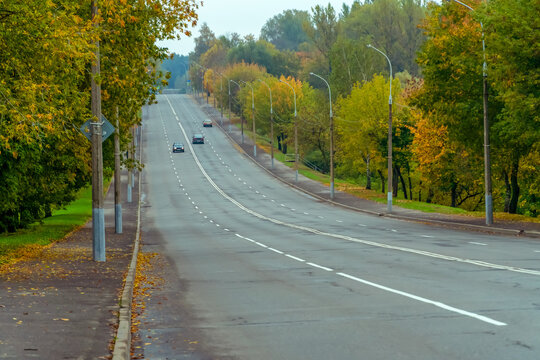 Four lane highway with a small number of cars on a cloudy colorful autumn day