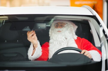 Authentic Santa Claus driving his modern car, outdoors