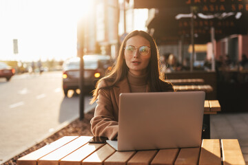 Beautiful business woman working on laptop outside her office, freelance concept. Young attractive business woman sitting on the stairs and using modern laptop.