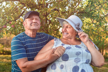 Authentic outdoor shot of old couple having fun in the garden and blessed with love. During their game man is trying to kiss his partner and she is laughing out loud. Love and family concept.