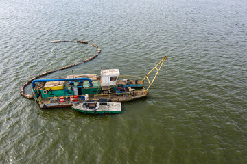 The old river vessel is working to clean up the reservoir, shooting from a drone, sunny weather.
