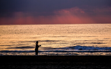 Fototapeta na wymiar woman fishing in the sea at sunrise