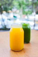 orange juice and green smoothie on a wooden table